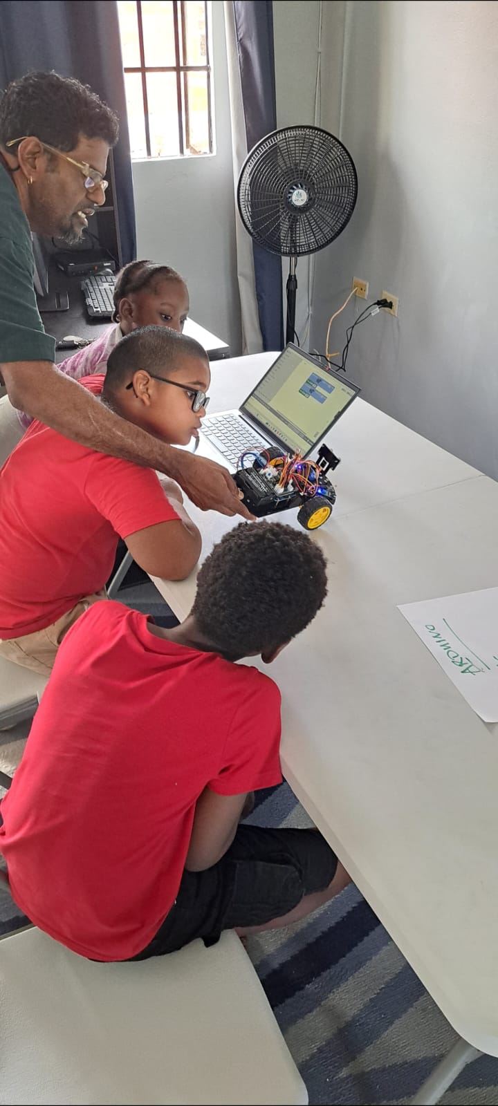 Mr. Boodram working with students on a robotics project